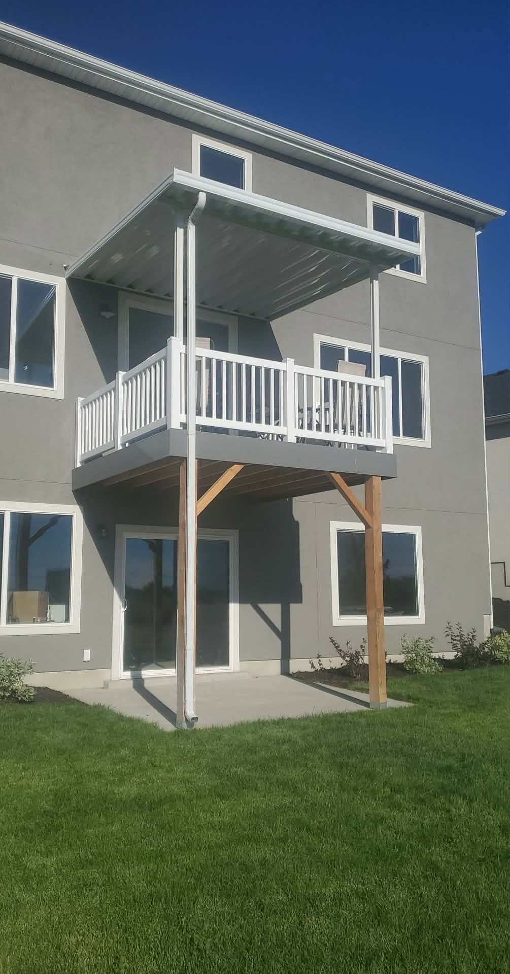 Covered balcony with white railings on a gray two-story home