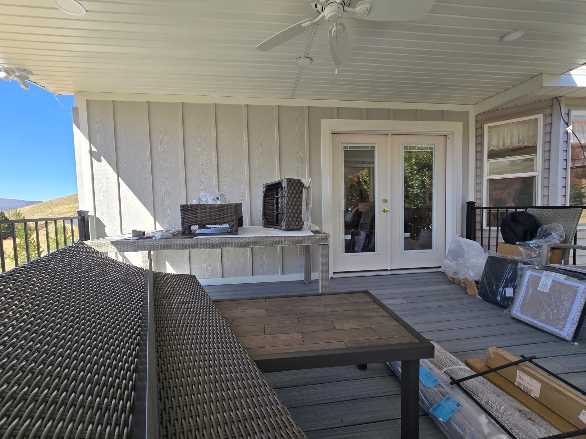 Furnished covered deck with board-and-batten siding and glass doors