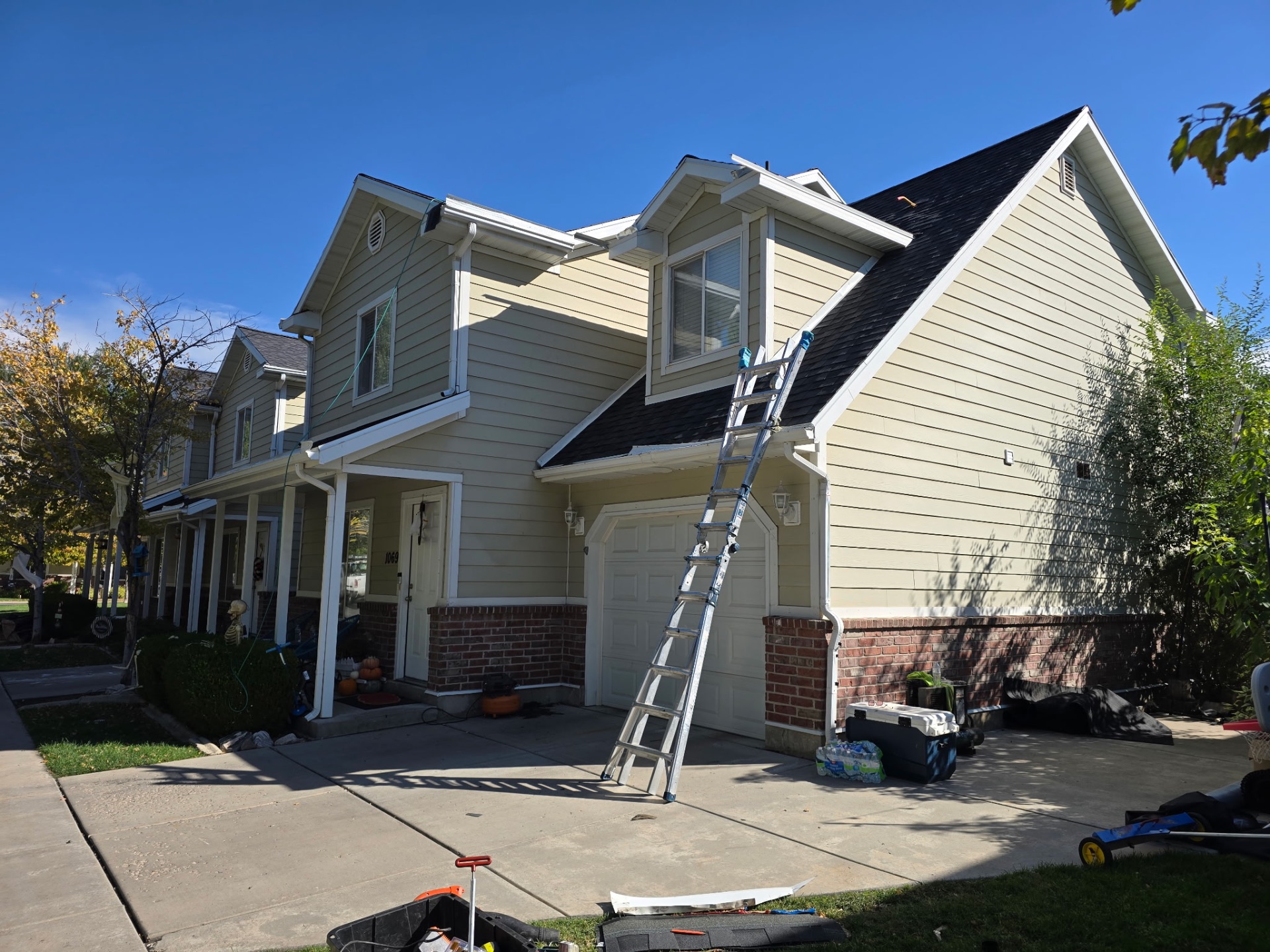 Two-story home with a ladder against the roof during gutter work