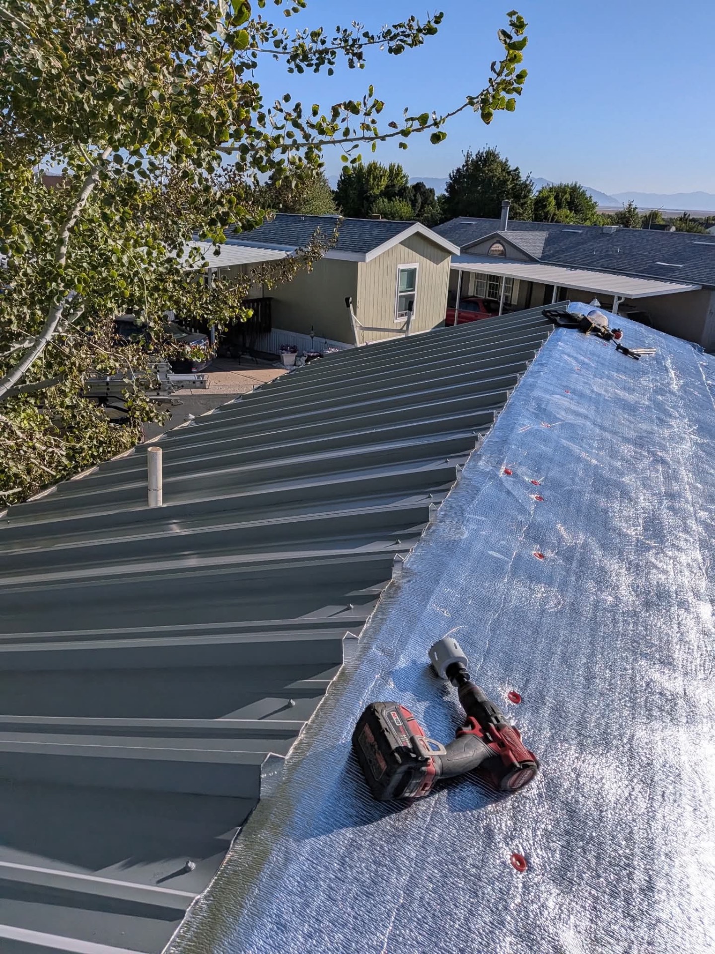 Cordless drill and fasteners on a metal roof underlayment during installation