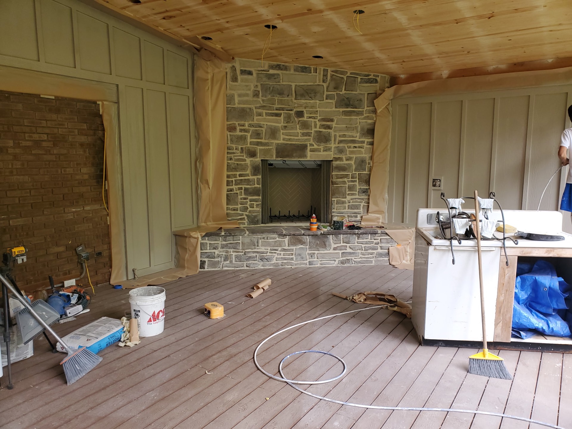 Covered porch under construction with wood ceiling and stone fireplace