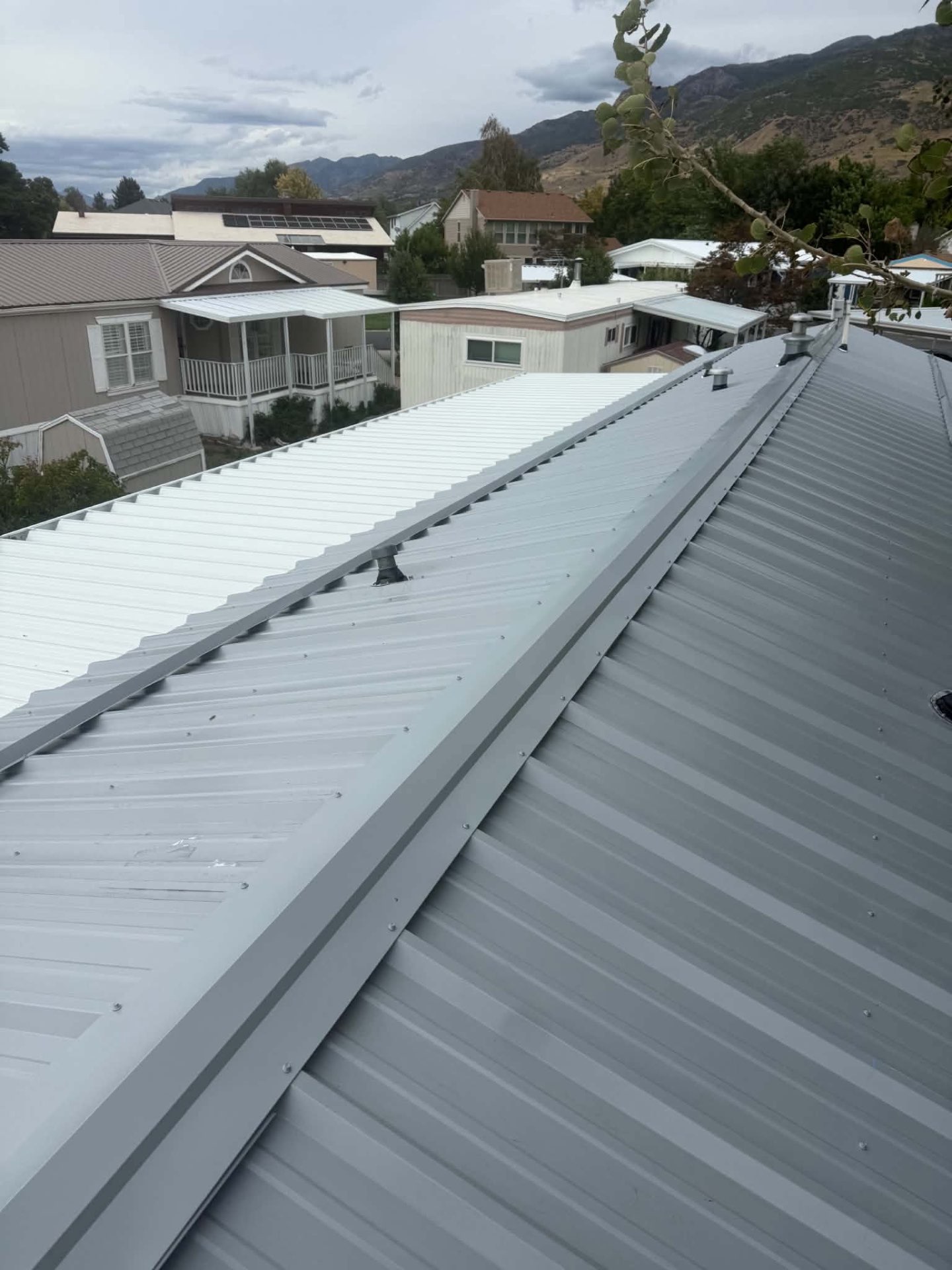 Gray corrugated metal roof panels and ridge detail on a completed roof